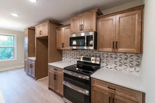 a kitchen with stainless steel appliances granite countertop a sink a stove and a window