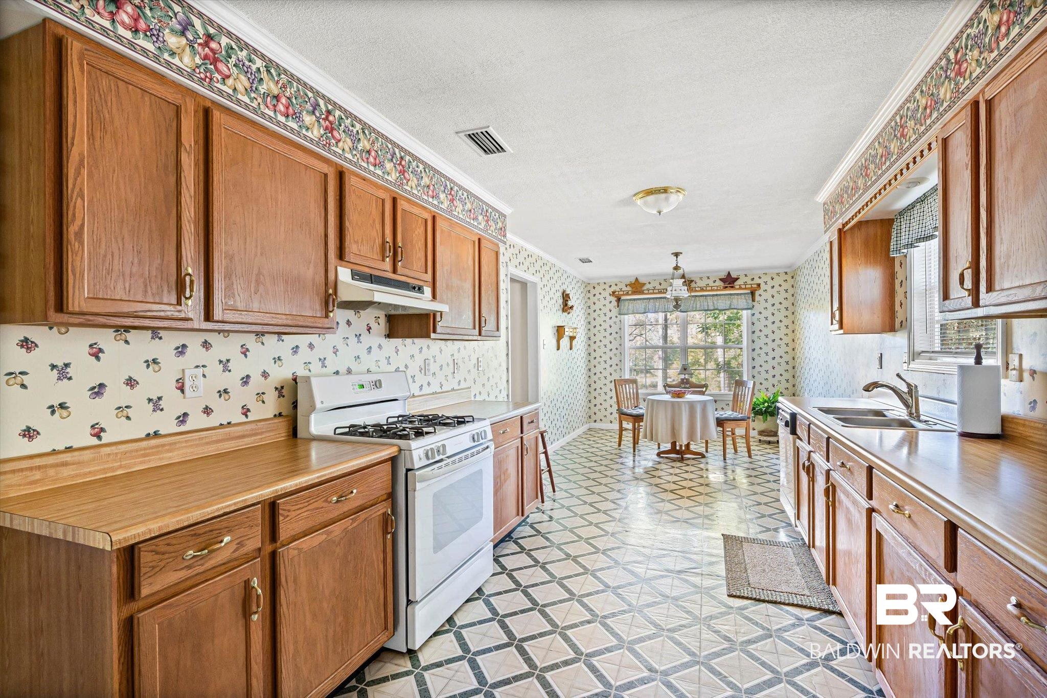 431 Simms Drive Saraland, AL 36571 - Photo 8 of 34 Kitchen featuring gas range gas stove, wallpapered walls, light countertops, brown cabinets, and under cabinet range hood