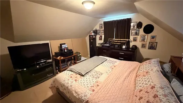 a bedroom with a bed and a flat tv screen on dresser