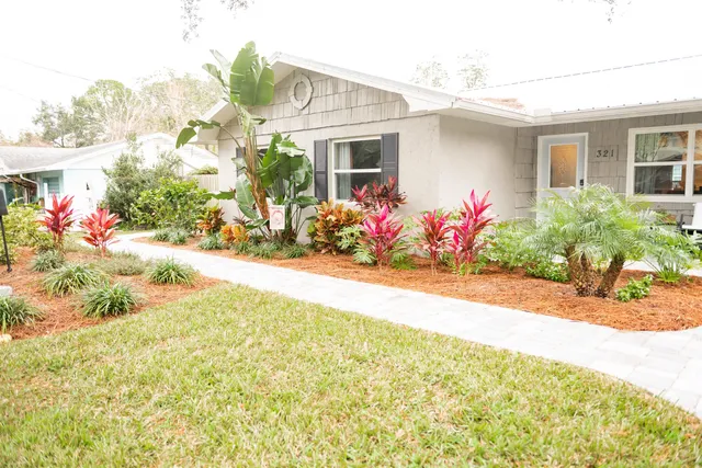 a front view of house and yard with beautiful flowers