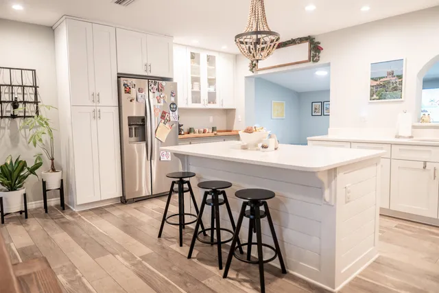 a kitchen with stainless steel appliances a white table chairs and a refrigerator
