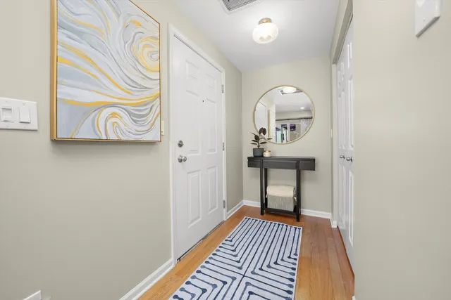 a view of a hallway with wooden floor and a bathroom