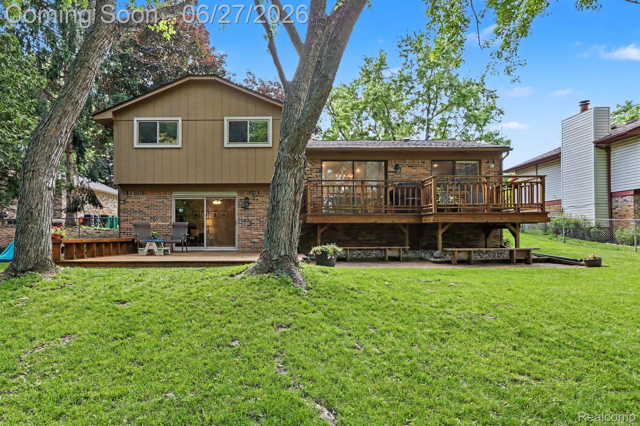 5134 Old Cove Road Clarkston, MI 48346 - Photo 27 of 27 Split-level residence featuring a brick and siding exterior, expansive lawn, multi-level wood deck, and multiple sliding glass doors