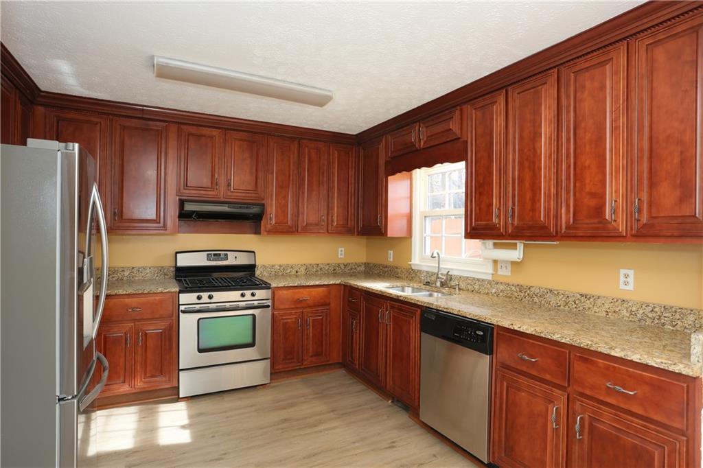 4981 Shallow Ridge Road Northeast Kennesaw, GA 30144 - Photo 14 of 36 a kitchen with kitchen island granite countertop wooden cabinets stainless steel appliances a sink and a window