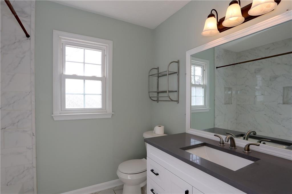 4981 Shallow Ridge Road Northeast Kennesaw, GA 30144 - Photo 28 of 36 a bathroom with a granite countertop sink a toilet and mirror