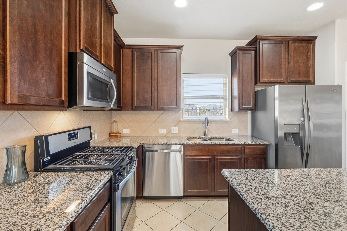 160 Albatross Cove Buda, TX 78610 - Photo 4 of 36 a kitchen with stainless steel appliances granite countertop a stove top oven a sink dishwasher and wooden cabinets