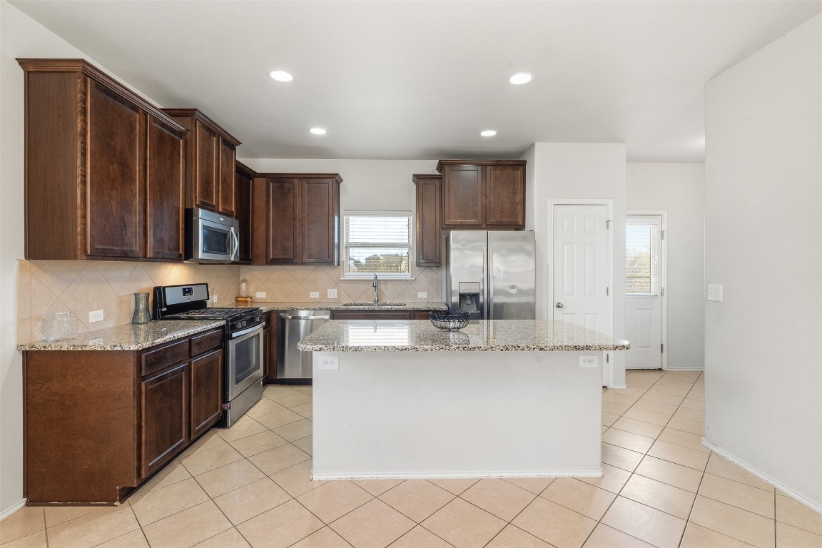 160 Albatross Cove Buda, TX 78610 - Photo 5 of 36 a kitchen with stainless steel appliances granite countertop a stove a sink and a refrigerator