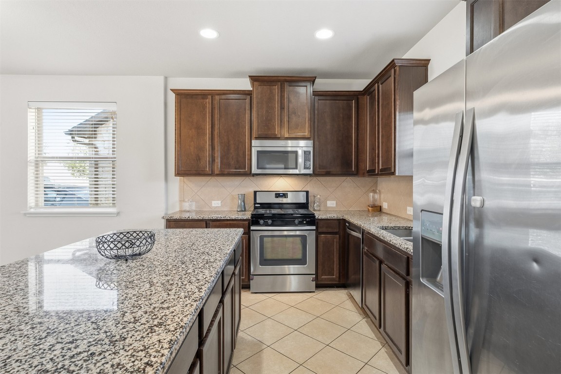 160 Albatross Cove Buda, TX 78610 - Photo 7 of 36 a kitchen with granite countertop a refrigerator and a stove top oven