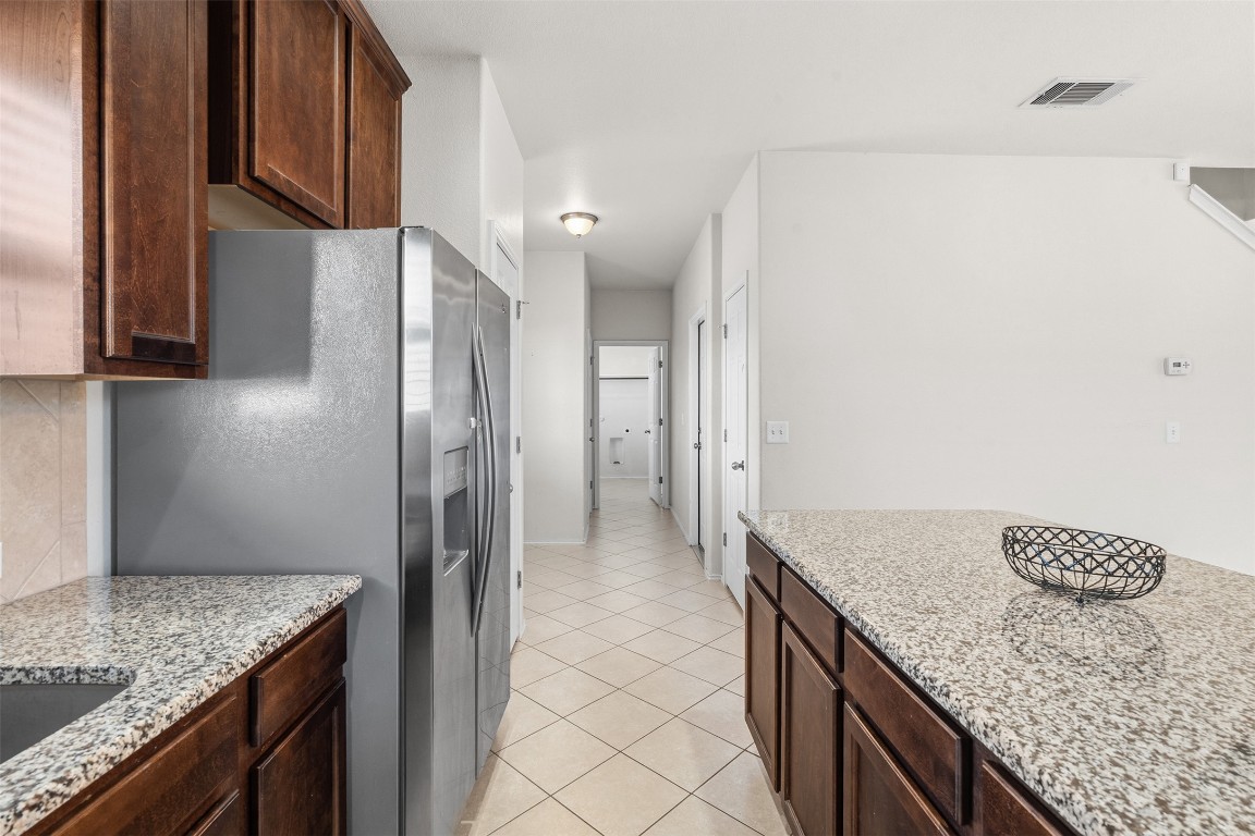 160 Albatross Cove Buda, TX 78610 - Photo 8 of 36 a kitchen with granite countertop a sink and a refrigerator