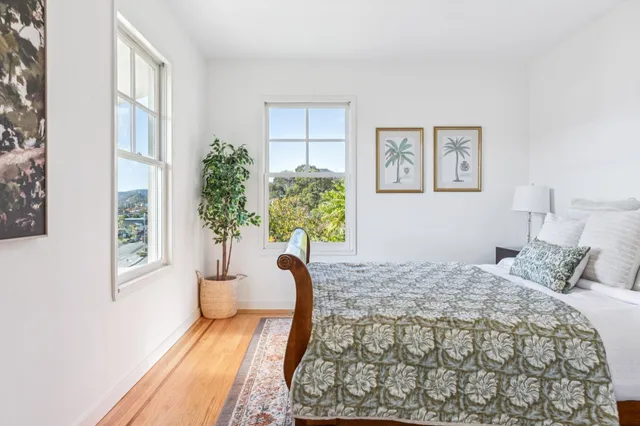 a bedroom with a bed table flowerpot and window