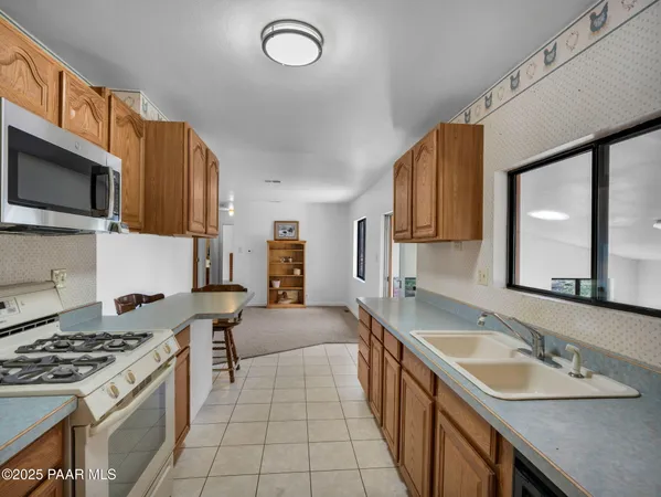 a kitchen with stainless steel appliances granite countertop a sink a stove top oven a refrigerator with grey cabinets