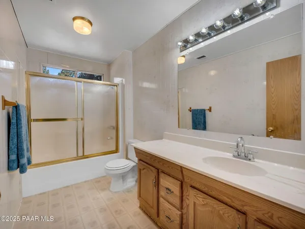 a spacious bathroom with a granite countertop sink a toilet a mirror and shower