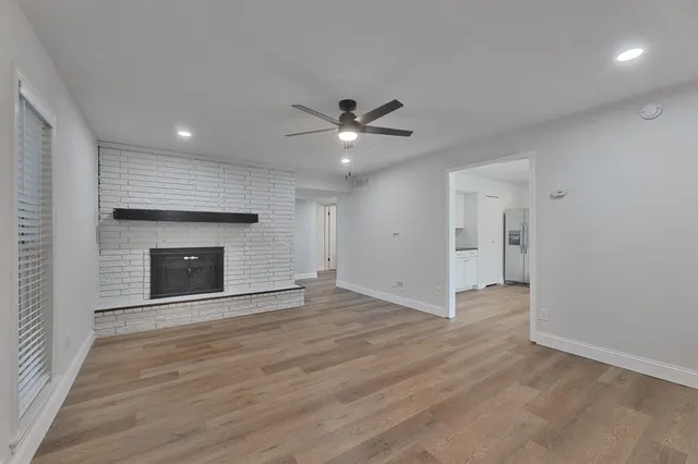 an empty room with wooden floor a fireplace and a window