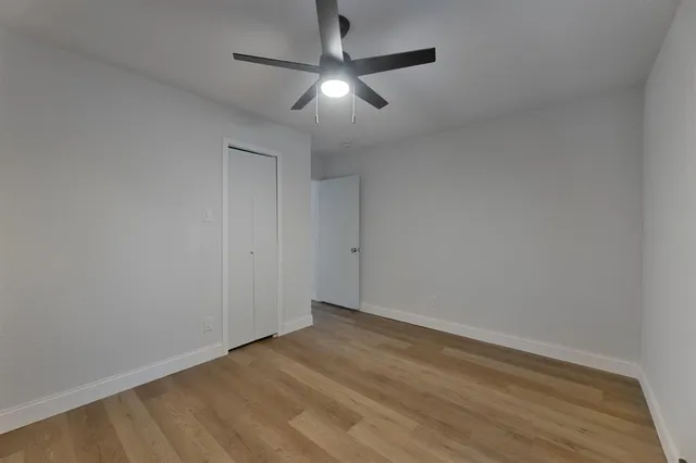 an empty room with a ceiling fan and wooden floor