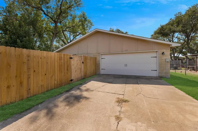 a view of backyard of house with wooden fence