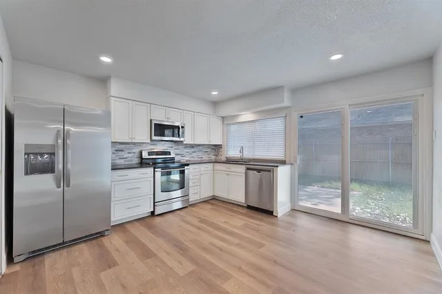 a large kitchen with white cabinets and stainless steel appliances