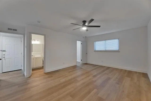 a view of an empty room with a window and wooden floor