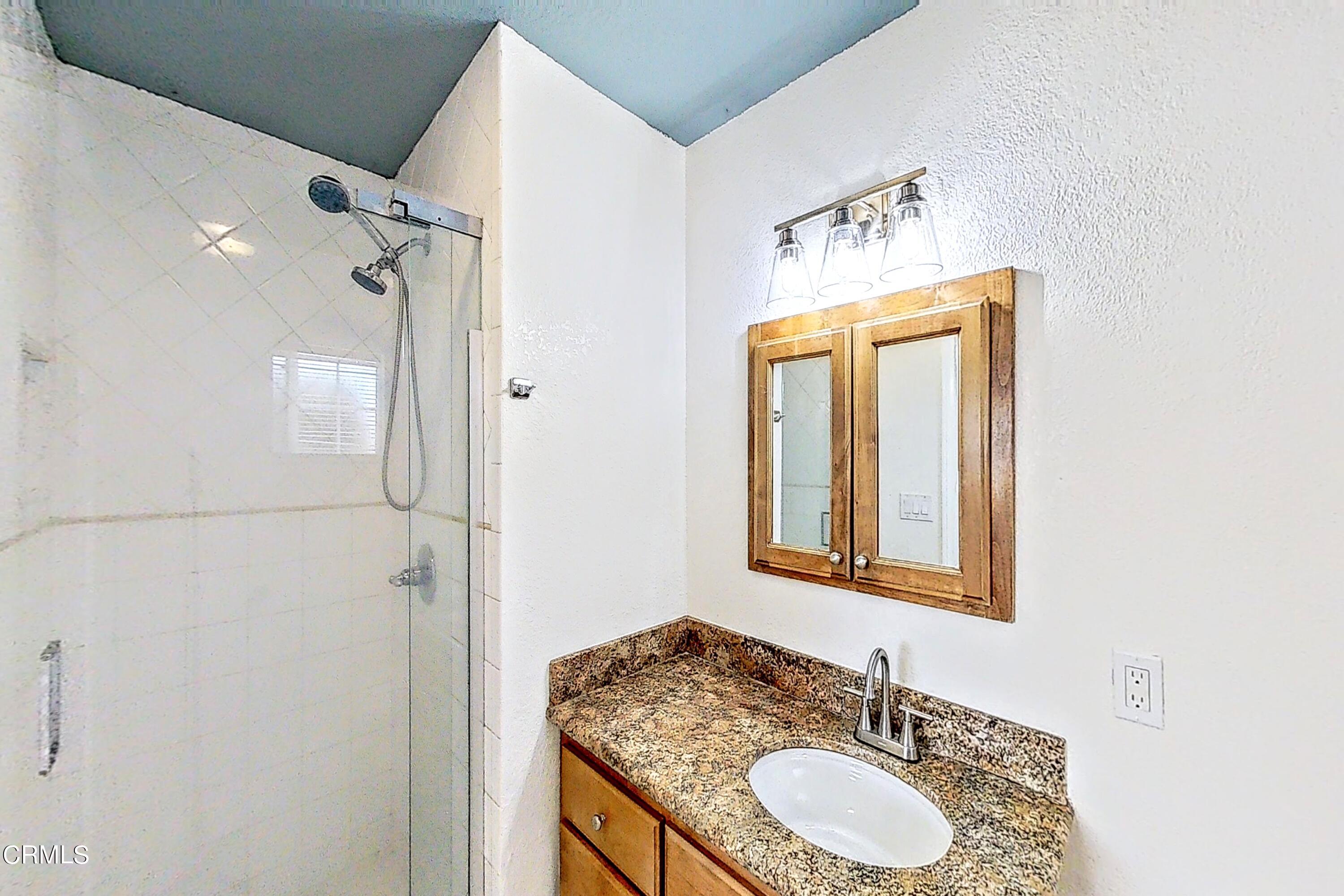 1830 Claremont Drive Oxnard, CA 93035 - Photo 25 of 36 a bathroom with a granite countertop sink a mirror and a shower