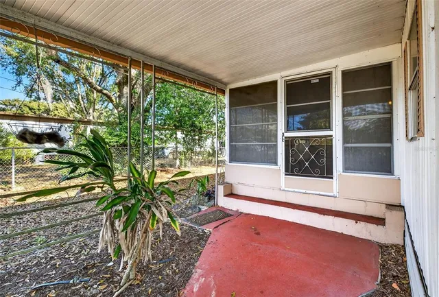 a view of a porch with a floor to ceiling window and potted plants