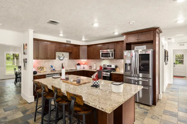 a kitchen with granite countertop a table chairs microwave and refrigerator