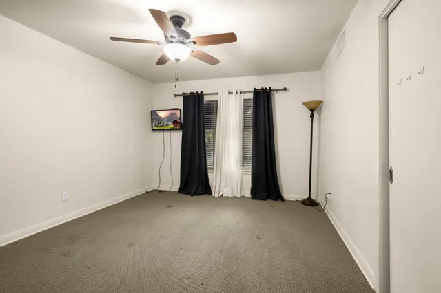 an empty room with closet and a ceiling fan
