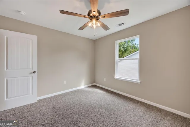 an empty room with windows and fan