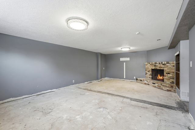 1410 Sumac Drive Logan, UT 84321 - Photo 23 of 28 Spacious interior with an exposed concrete floor, a brick fireplace with a hearth, and modern flush-mount lighting fixtures