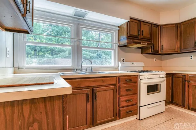a kitchen with stainless steel appliances granite countertop a sink a stove a microwave cabinets and a dining table