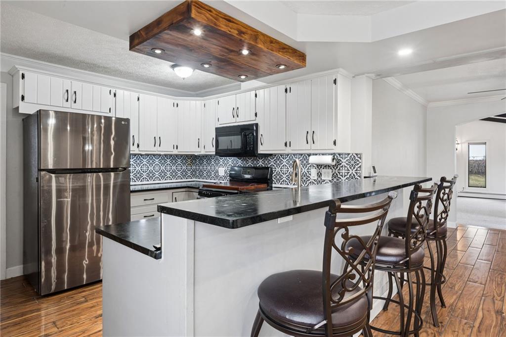 255 Poplar Street Monroeville, PA 15146 - Photo 13 of 44 A wood-accented lighting feature and natural wood-look flooring bring warmth and texture to the space, while the open layout allows seamless flow into the adjoining living areas. A raised bar with seating provides the perfect spot for casual dining, morning coffee, or gathering with guests.