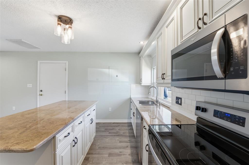 5153 Turquoise Lane, Unit 102 New Port Richey, FL 34652 - Photo 12 of 29 a kitchen with stainless steel appliances granite countertop a stove a microwave and a sink