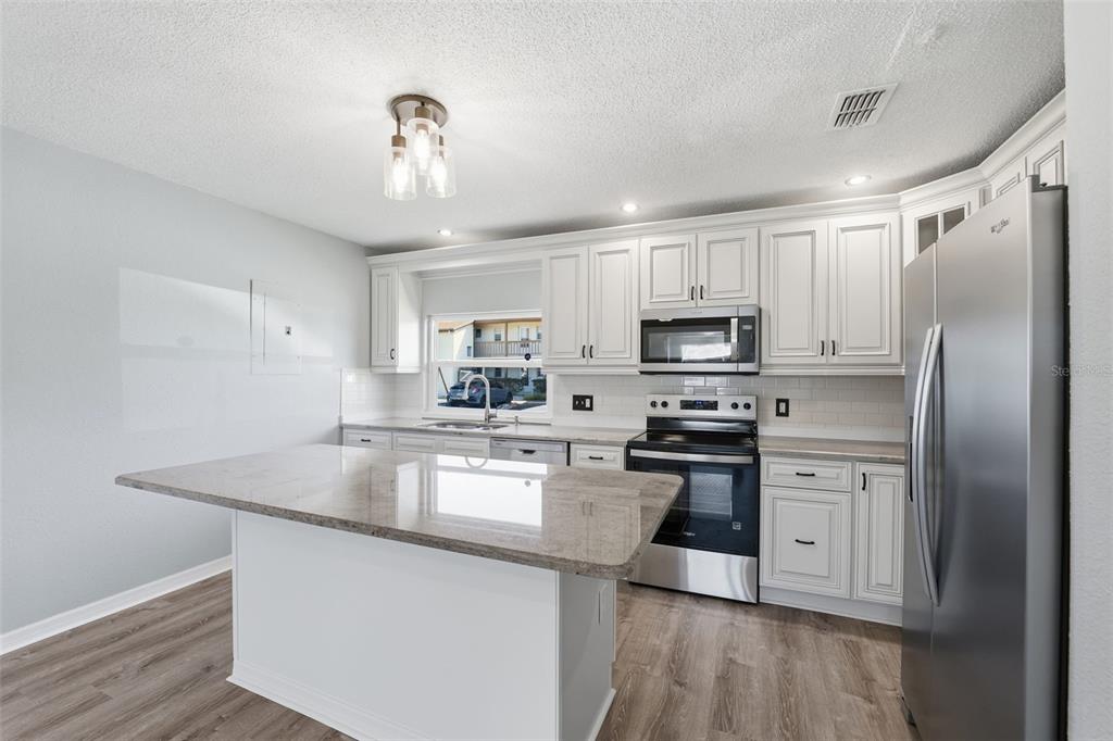 5153 Turquoise Lane, Unit 102 New Port Richey, FL 34652 - Photo 10 of 29 a kitchen with kitchen island granite countertop stainless steel appliances a stove refrigerator sink and microwave