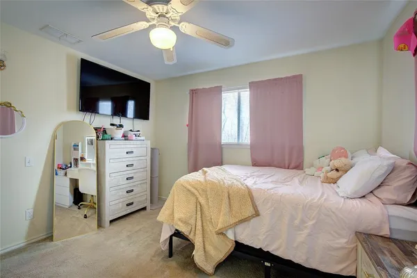 a bedroom with a bed and a flat tv screen on dresser