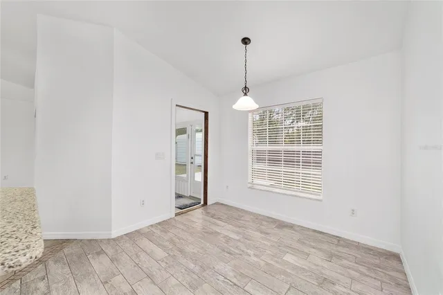 a view of a hallway with wooden floor and a bathroom