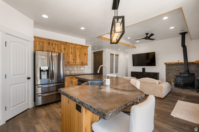 62 North Lucky 7 Road Veyo, UT 84782 - Photo 10 of 43 Kitchen featuring a breakfast bar area, stainless steel refrigerator with ice dispenser, a center island with sink, a wood stove, and dark wood-style floors