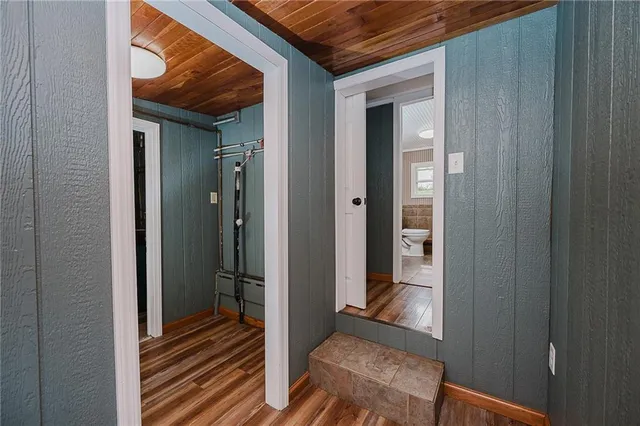 a view of a hallway with wooden floor and a bathroom