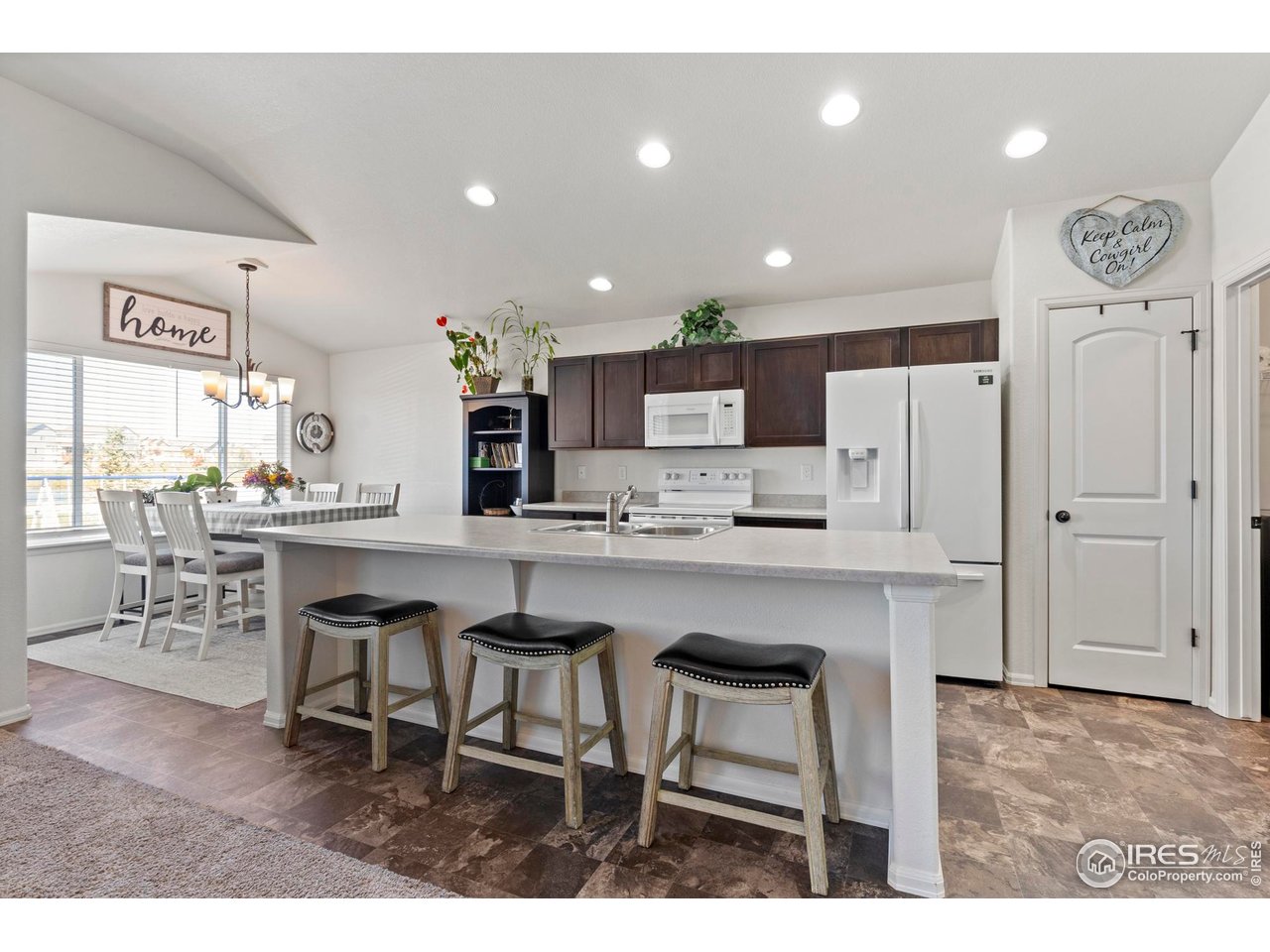 941 Barasingha Street Severance, CO 80550 - Photo 12 of 46 a kitchen with a table chairs refrigerator and cabinets