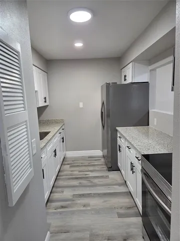 a kitchen with granite countertop white cabinets and refrigerator
