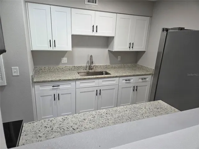a kitchen with granite countertop a sink stove and cabinets