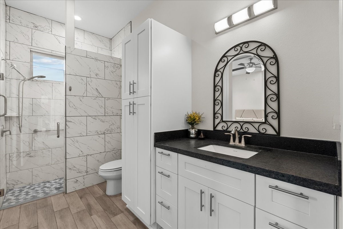 3706 Tower Road Santa Fe, TX 77517 - Photo 31 of 48 a bathroom with a granite countertop sink a toilet and a mirror