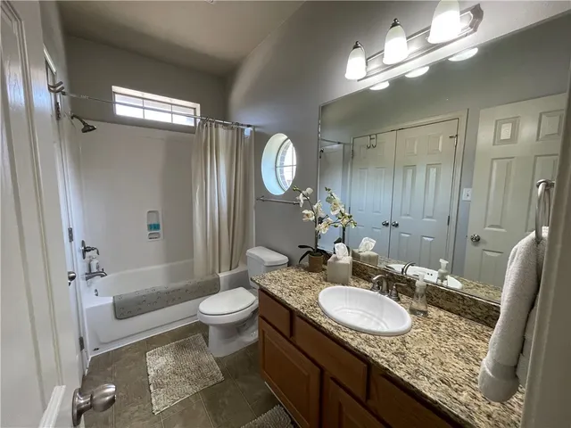 a bathroom with a granite countertop sink toilet a mirror a vanity and shower
