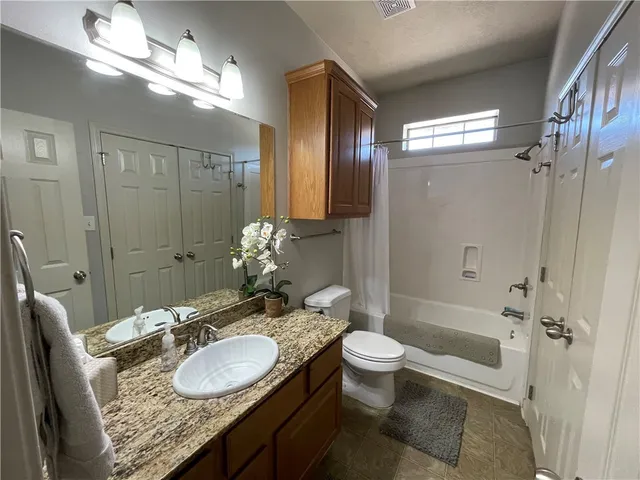 a bathroom with a granite countertop sink a toilet a mirror and shower
