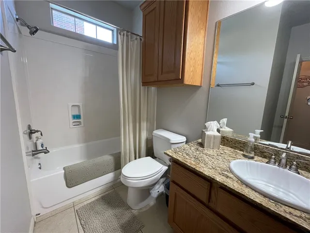 a bathroom with a granite countertop toilet sink and mirror