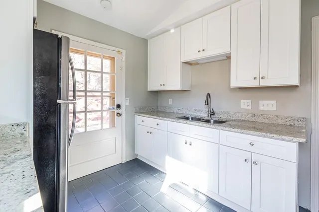 a kitchen with granite countertop white cabinets and sink