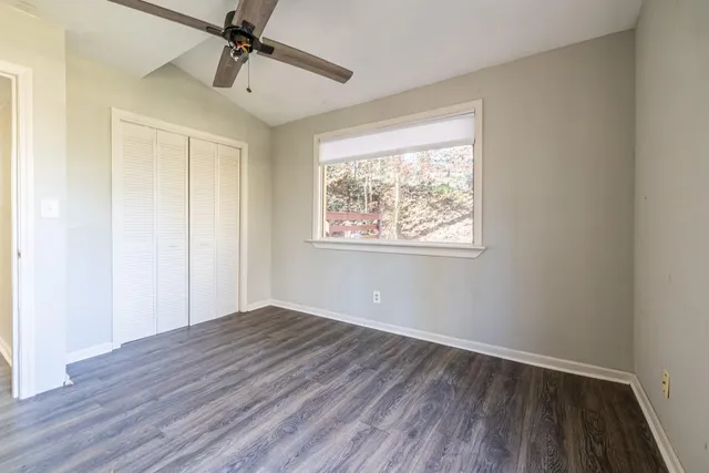 a view of an empty room with wooden floor and a window