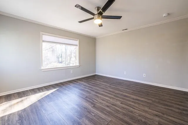an empty room with wooden floor and windows
