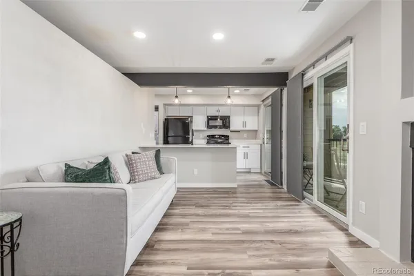 a large white kitchen with kitchen island a large counter top and stainless steel appliances