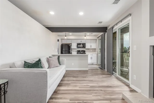 a large white kitchen with kitchen island a large counter top and stainless steel appliances