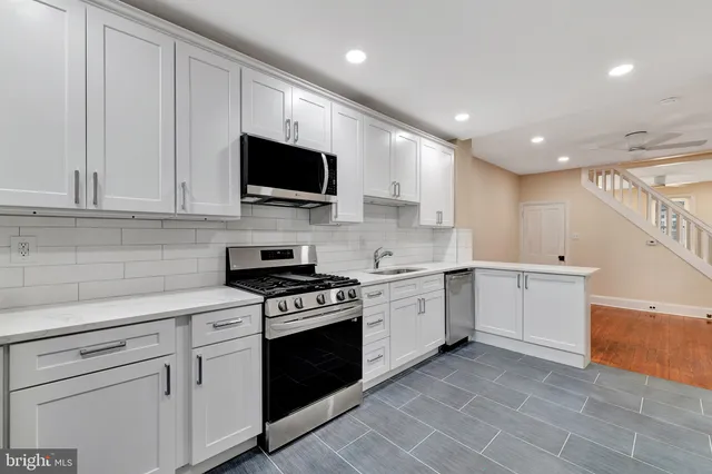 a kitchen with granite countertop a sink a stove and cabinets