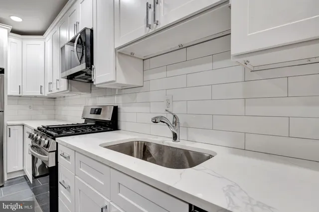 a view of a kitchen with stainless steel appliances granite countertop a sink and cabinets