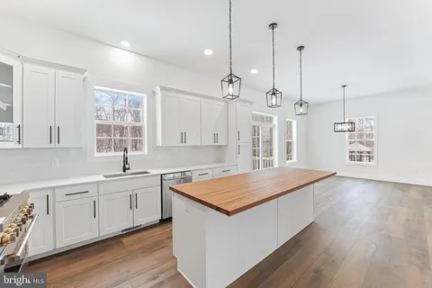 a hall with kitchen island a stove a sink dishwasher and a wooden floor